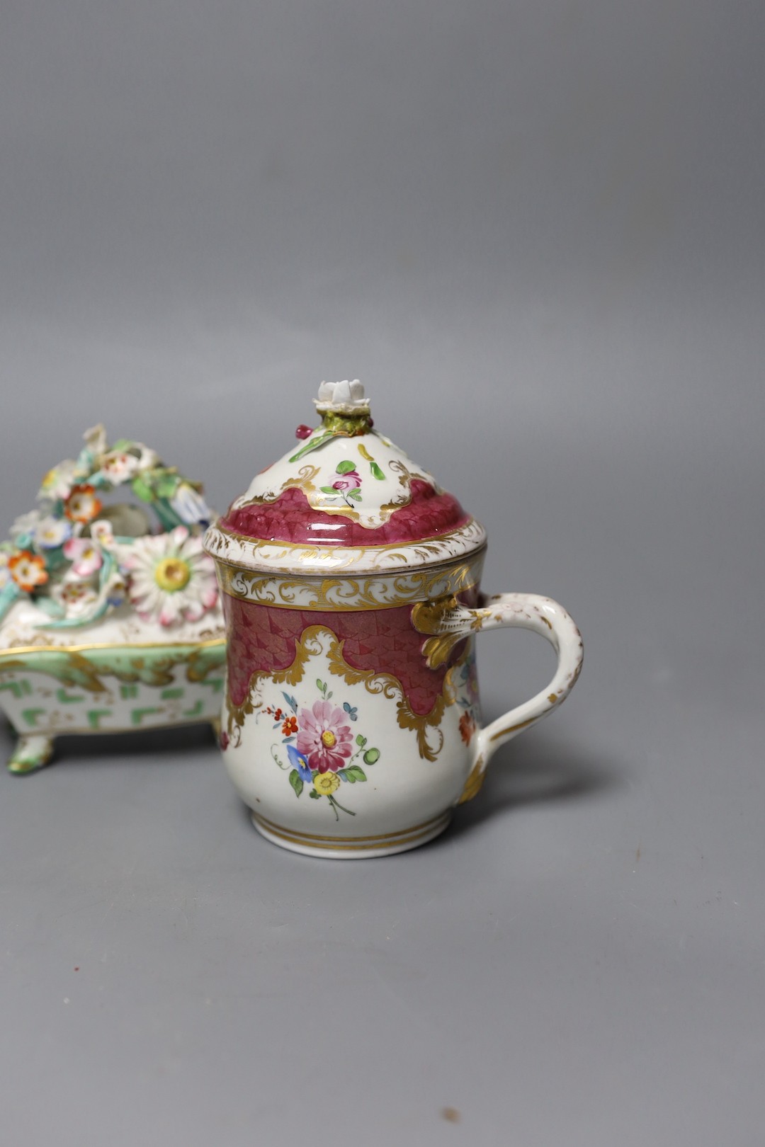 An 18th century Mennecy porcelain cup and cover, a Meissen style cup and cover, an English porcelain floral encrusted double inkwell and cover and a similar jar and cover